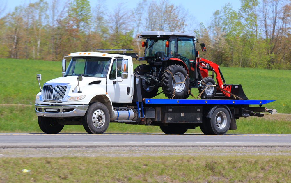 Flat bed tow truck hauling a Tractor