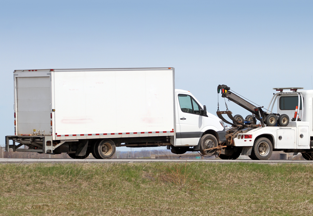 white tow truck pulling a large box truck
